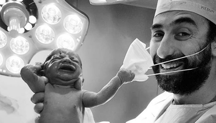 نوزائیدہ بچے کی ڈاکٹر کے چہرے سے ماسک ہٹانے کی کوشش