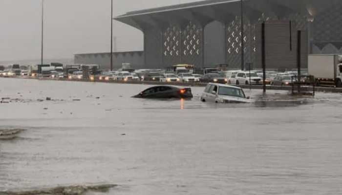 Flood conditions on the road after heavy rain, vehicles stuck on one lane, floating on another.