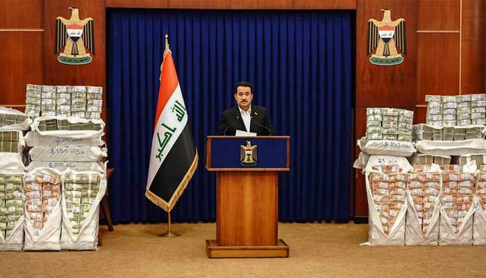 عراقی وزیراعظم شیعہ السوڈانی تقریر کر رہے ہیں، قریب ہی برآمد کی گئی رقم موجود ہے۔