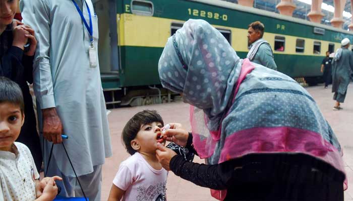 لاہور ریلوے اسٹیشن پر خاتون رضاکار بچی کو پولیو سے بچاؤ کے قطرے پلا رہی ہیں۔