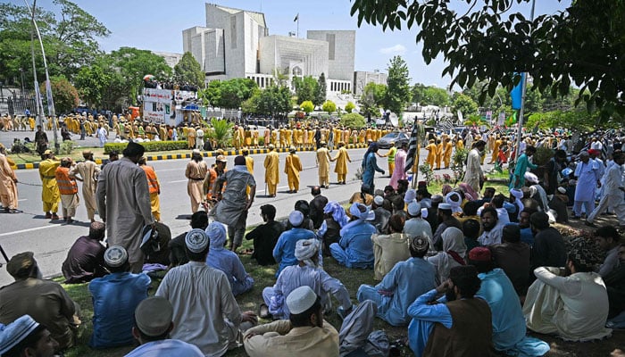 پی ڈی ایم کے کارکن سپریم کورٹ کے باہر دھرنا دیے بیٹھے ہیں۔ فوٹو: اے ایف پی