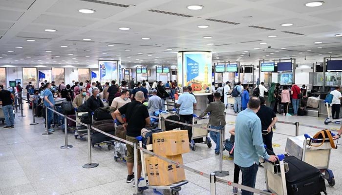 کویت انٹرنیشنل ایئرپورٹ پر مسافر قطاروں میں کھڑے ہیں۔