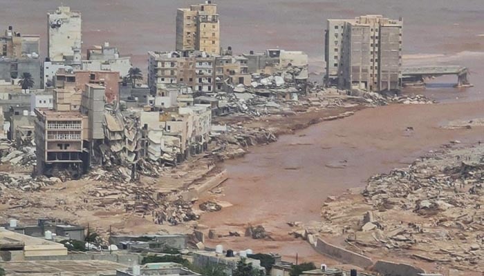 لیبیا میں سیلاب کے بعد کی تباہ کاری، عمارتیں زمیں بوس ہیں جبکہ سیلابی پانی کا ریلا موجود ہے۔