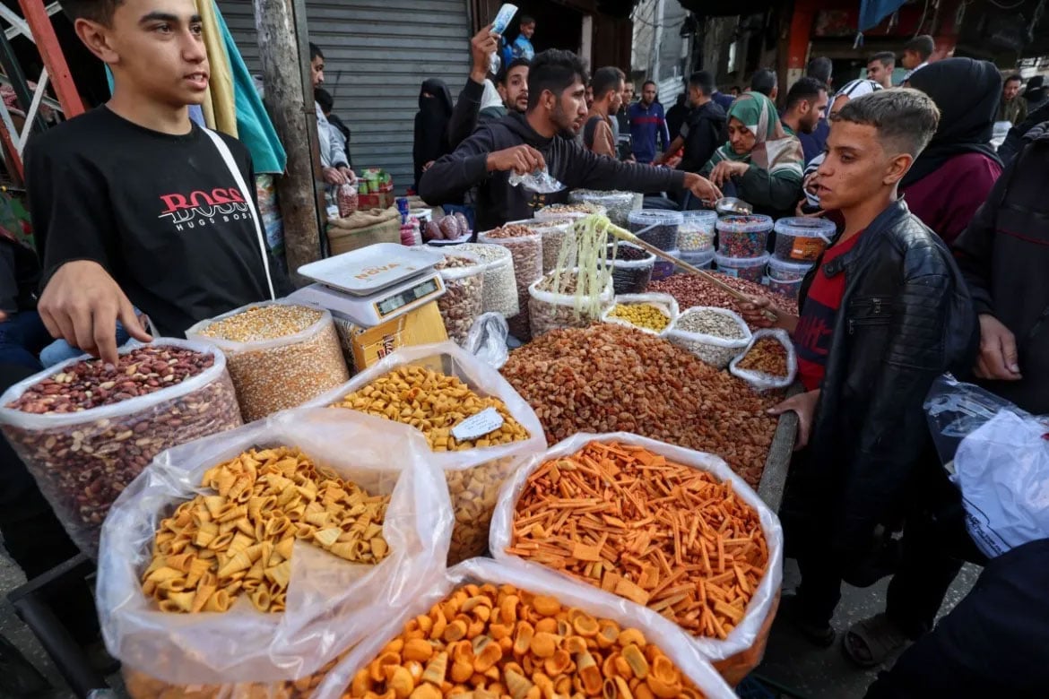 فلسطینی رفح کے ایک کھلے بازار میں خرید و فروخت کر رہے ہیں۔ [محمد عابد/اے ایف پی]