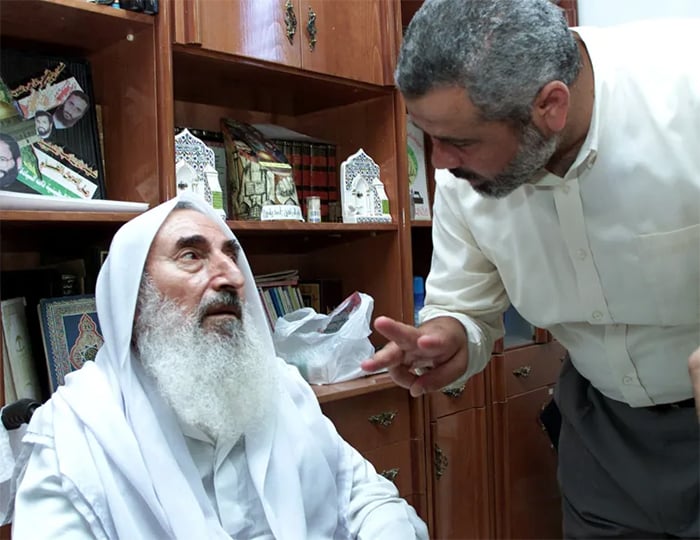 گھر میں نظربند ہونے کے بعد شیخ احمد یاسین جون 2002 میں غزہ میں اپنے دفتر کے ڈائریکٹر اسماعیل ہنیہ سے بات چیت کر رہے ہیں۔ فوٹو فائل: رائٹرز