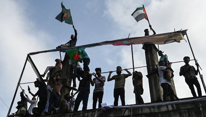 ڈھاکا یونیورسٹی کے قریب مظاہرین جشن منارہے ہیں اور بنگلادیشی پرچم کے ساتھ فلسطینی پرچم بھی لہرا رہے ہیں - فوٹو: اے ایف پی