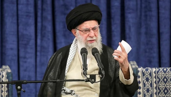 Irans supreme leader stands beside a rifle in a rare public appearance on Friday prayers