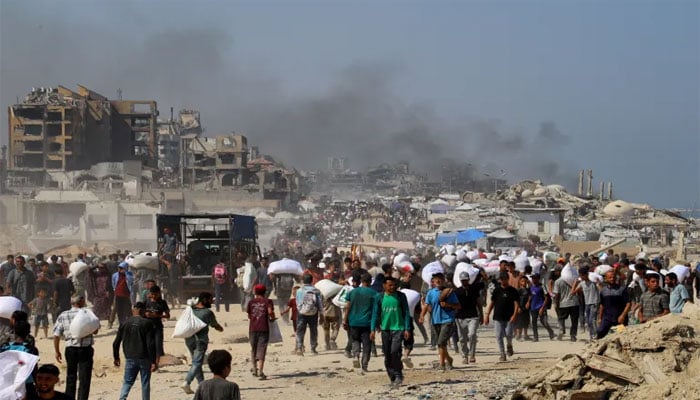 انسانیت سوز اسرائیلی مظالم اور بھوک پیاس سے بے حال فلسطینیوں کو مقتل میں نام نہاد غذائی فراہمی کا ایک منظر، پس منظر میں اسرائیلی حملوں سے اٹھنے والا دھواں مقتل کی نشاندہی کر رہا ہے—تصویر سوشل میڈیا