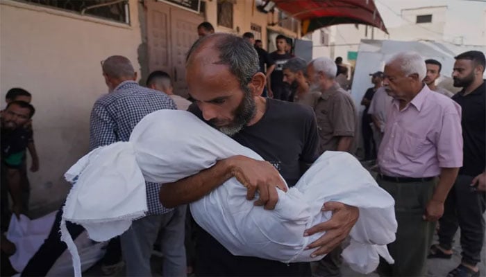 ایک غمزدہ باپ اپنے شہید بچے کی میت کو بوسہ دیتے ہوئے—تصویر سوشل میڈیا