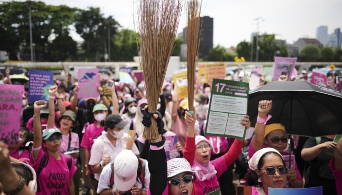 Indonesian women in pink, armed with broomsticks join protests