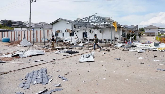 تھائی لینڈ اور کمبوڈیا کے درمیان تصادم میں تباہ ہونے والے سرحدی علاقے سے ایک شخص گزر رہا ہے—فوٹو: اے ایف پی