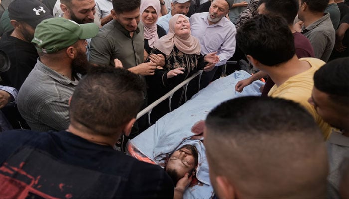 شہید ہونیوالے ایک فلسطینی کے جسد خاکی کے قریب اسکے لواحقین نوحہ کناں ہیں(تصویر سوشل میڈیا)۔